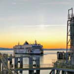 BC ferry vessel pulls into the docking structure with sunset in the background