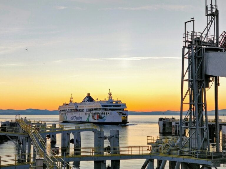 BC ferry vessel pulls into the docking structure with sunset in the background