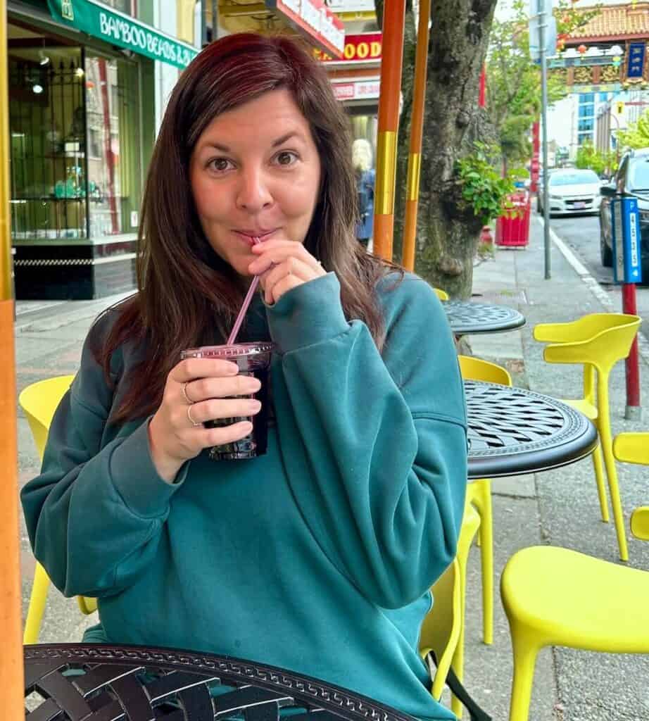 a woman sips juice through a straw at a patio restaurant in victoria bc